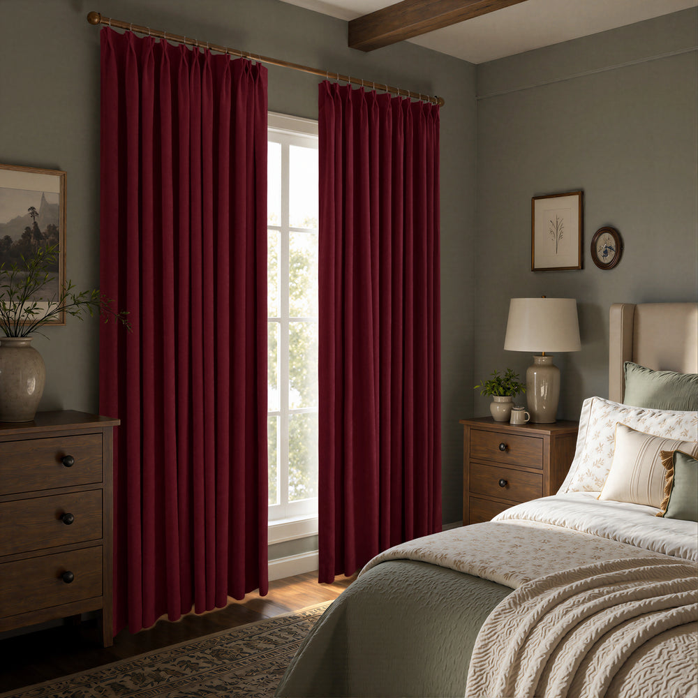 Deep burgundy curtain panels hanging on a gold rod in a styled bedroom with gray walls, wooden nightstands, and a bed.