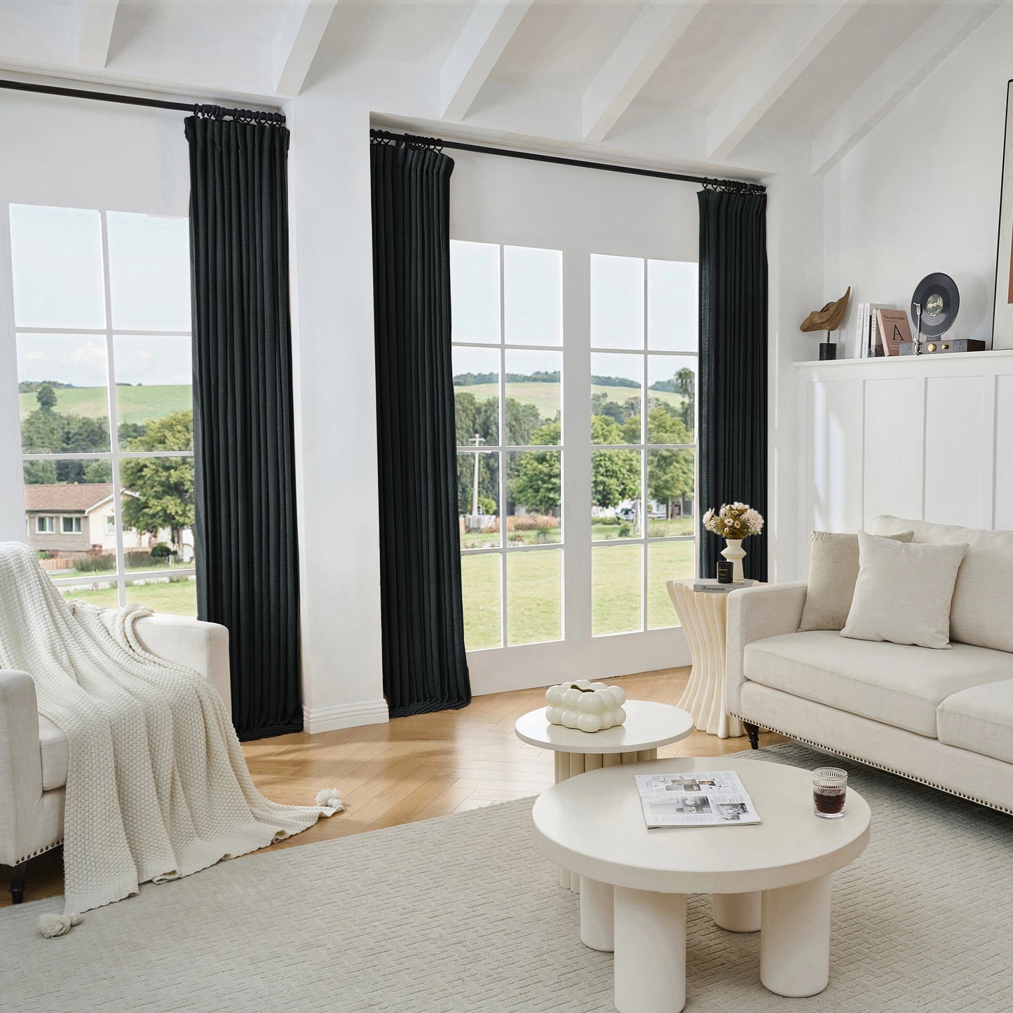 Living room with black viscose, polyester, and linen mixed fabric curtain, white sofa, and tables.