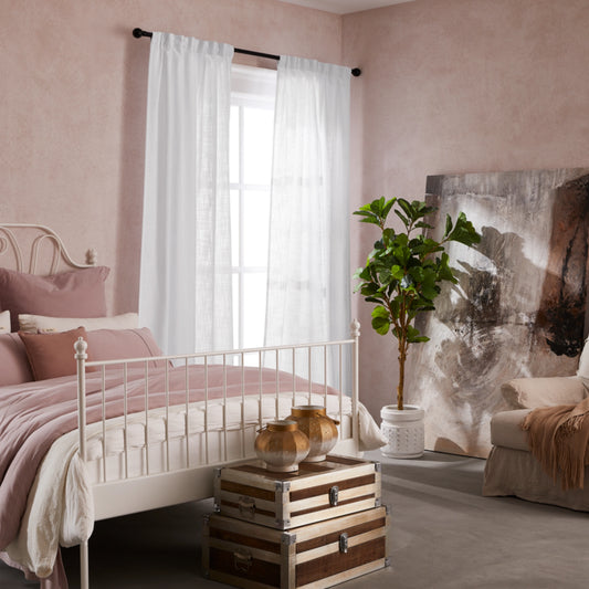 Bedroom with pink walls, white bed, decorative elements, and elegant soft bleached white linen-polyester mix pleated curtains.