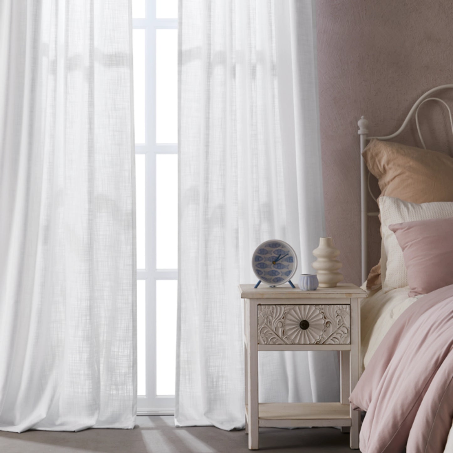 Bedroom with bleached ivory polyester-linen combination drapery panels, a nightstand, and a bed with pink bedding.