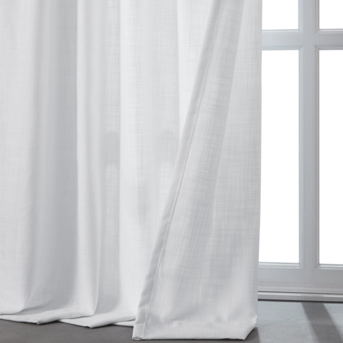 Cool bleached white linen-polyester blend lightweight curtain in front of a window.