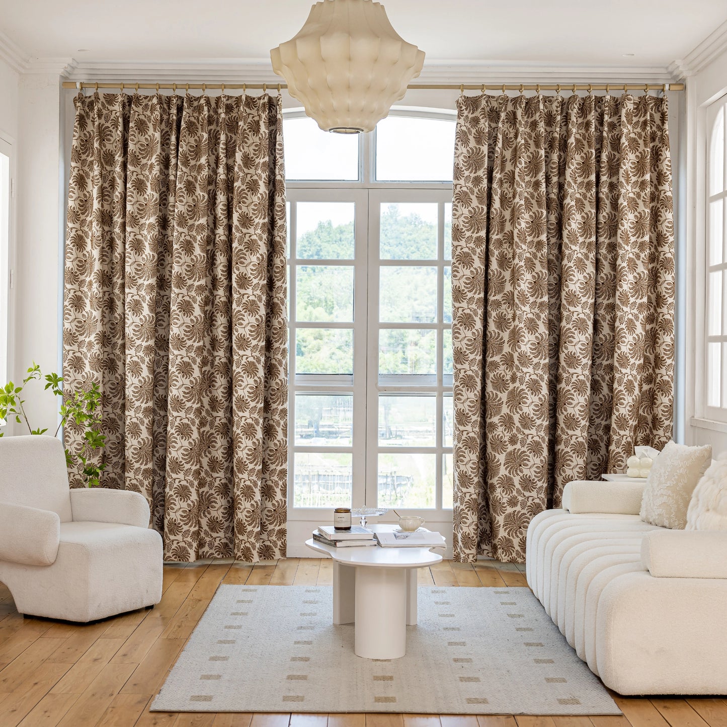 Living room with bohemian drapes featuring cocoa fern motifs, a white sofa, and a table.