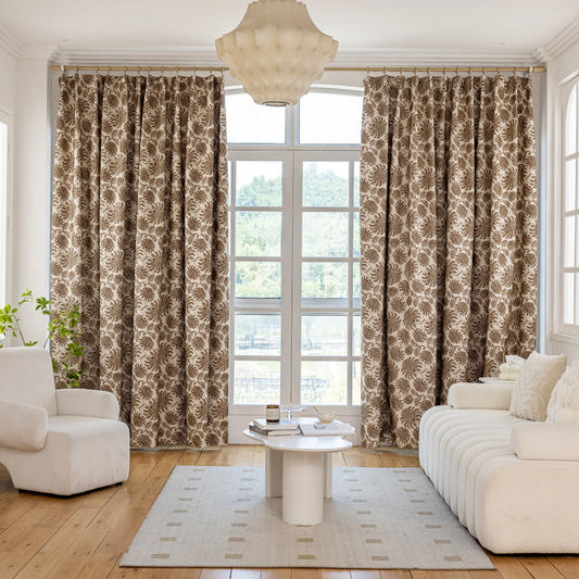 Living room with bohemian drapes featuring cocoa fern motifs, a white sofa, and a table.