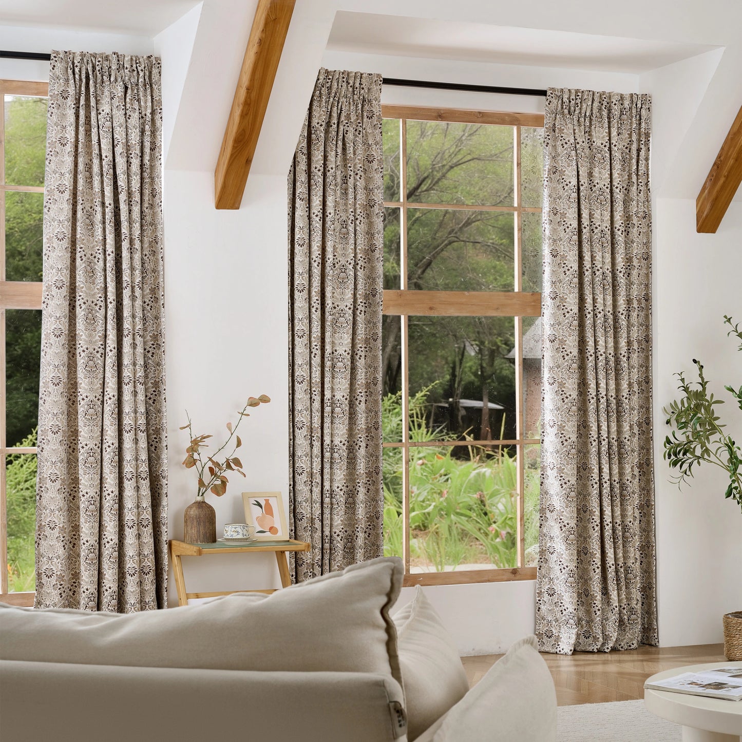 Bohemian-style floral drapes with a window in the background and a sofa in the foreground.