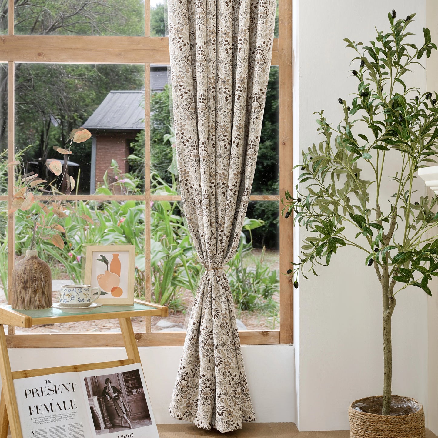 Earth-colored bohemian flower patterned curtains hanging in a window, with plants in the foreground.