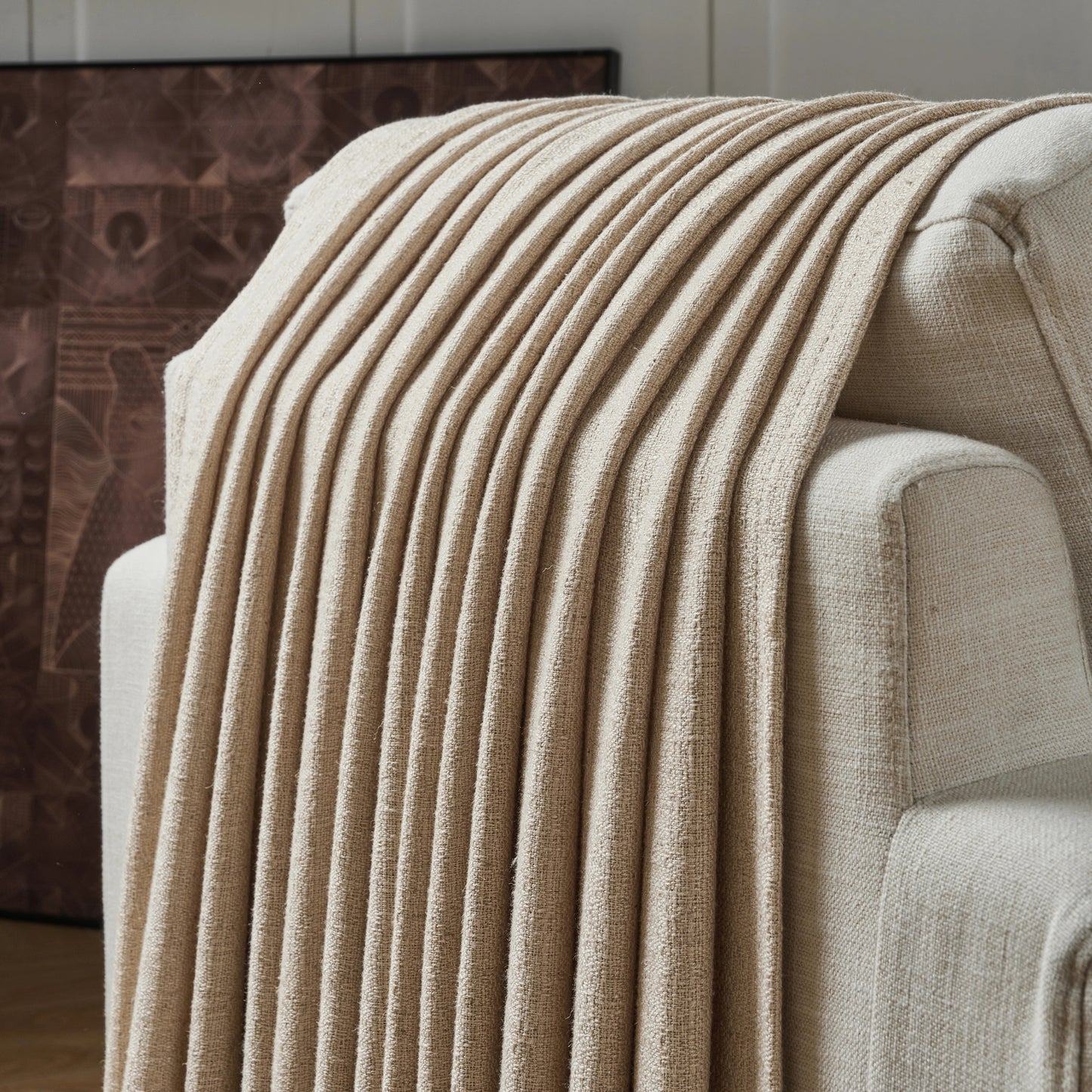 Camel textured curtain draped over a sofa, with a decorative wall in the background.