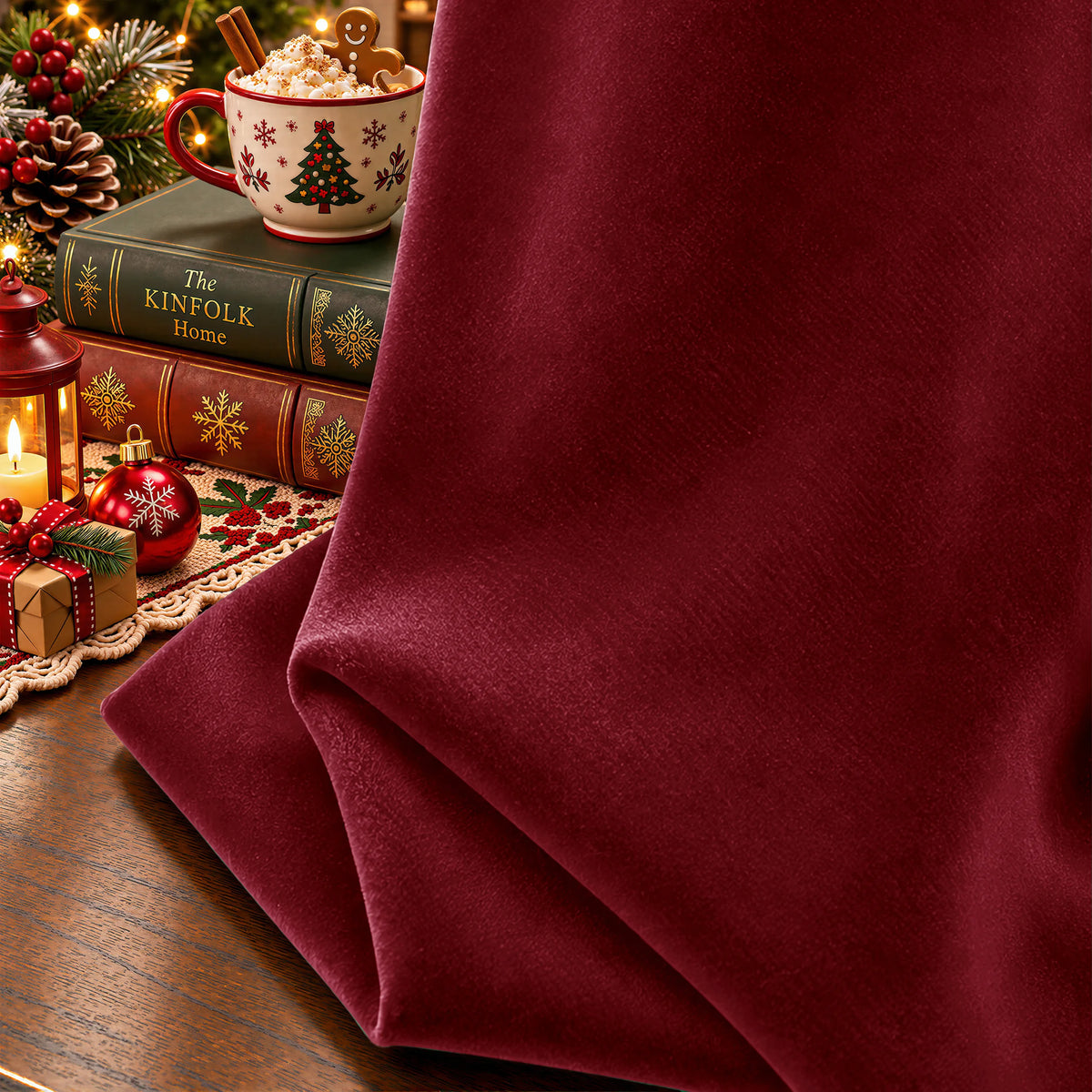 A draped piece of deep burgundy velvet fabric on a wooden table, styled with a vintage teacup and saucer and two decorative books.