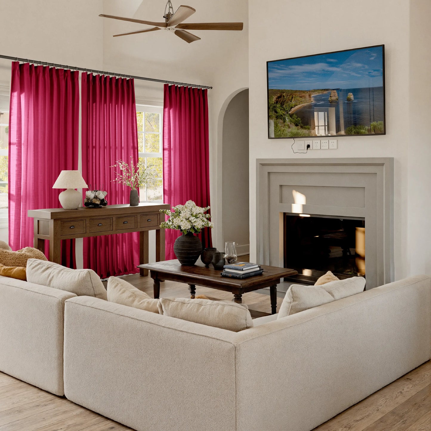 Living room with garnet curtains, beige sofa, and a television mounted on the wall.