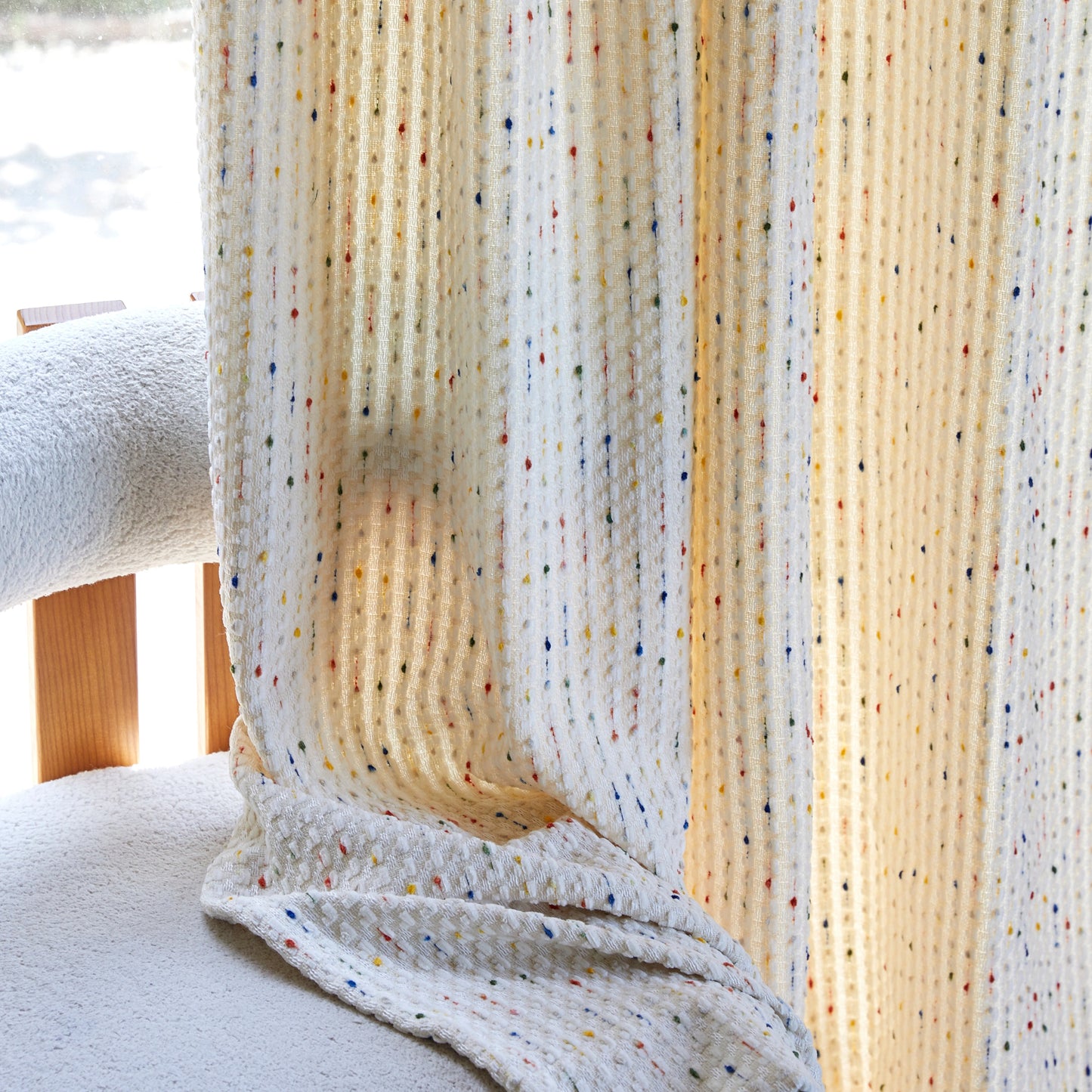 Textured fabric with colorful speckles draped over a chair
