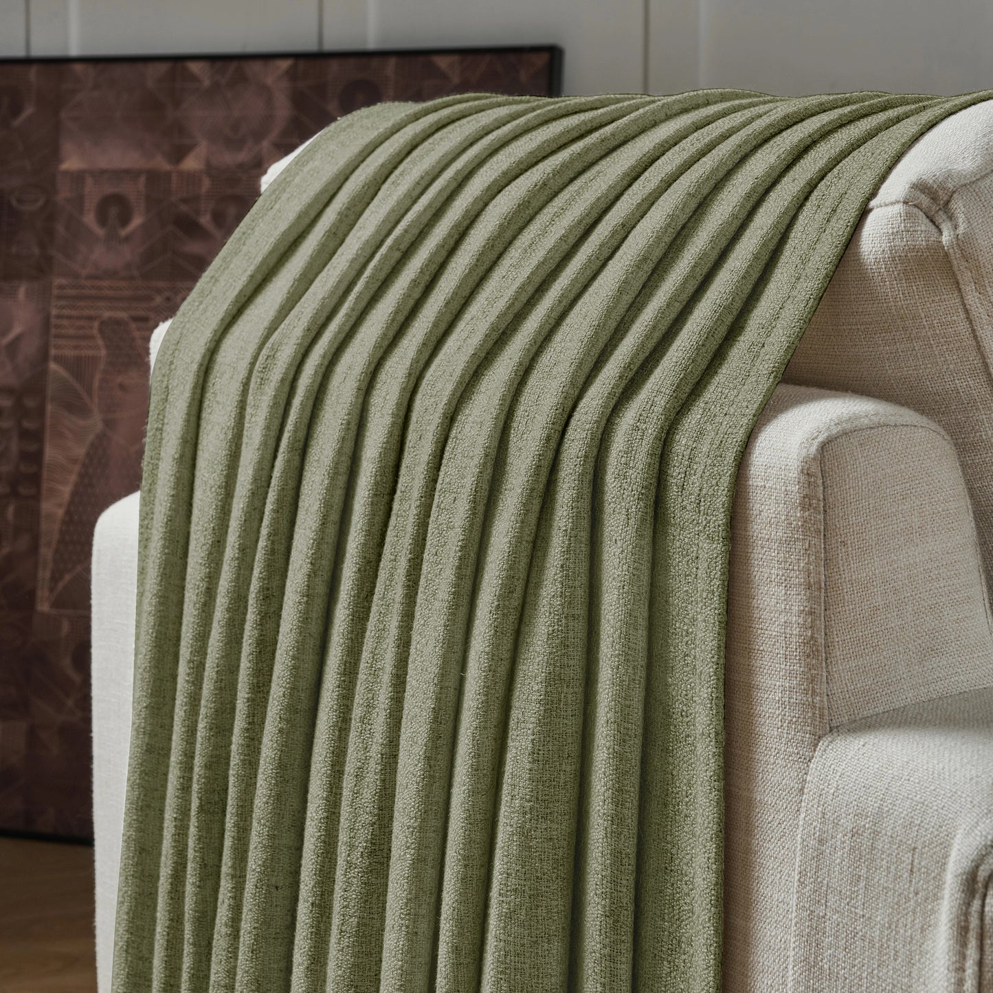 Dark gray textured curtain draped over a sofa, with a decorative wall in the background.