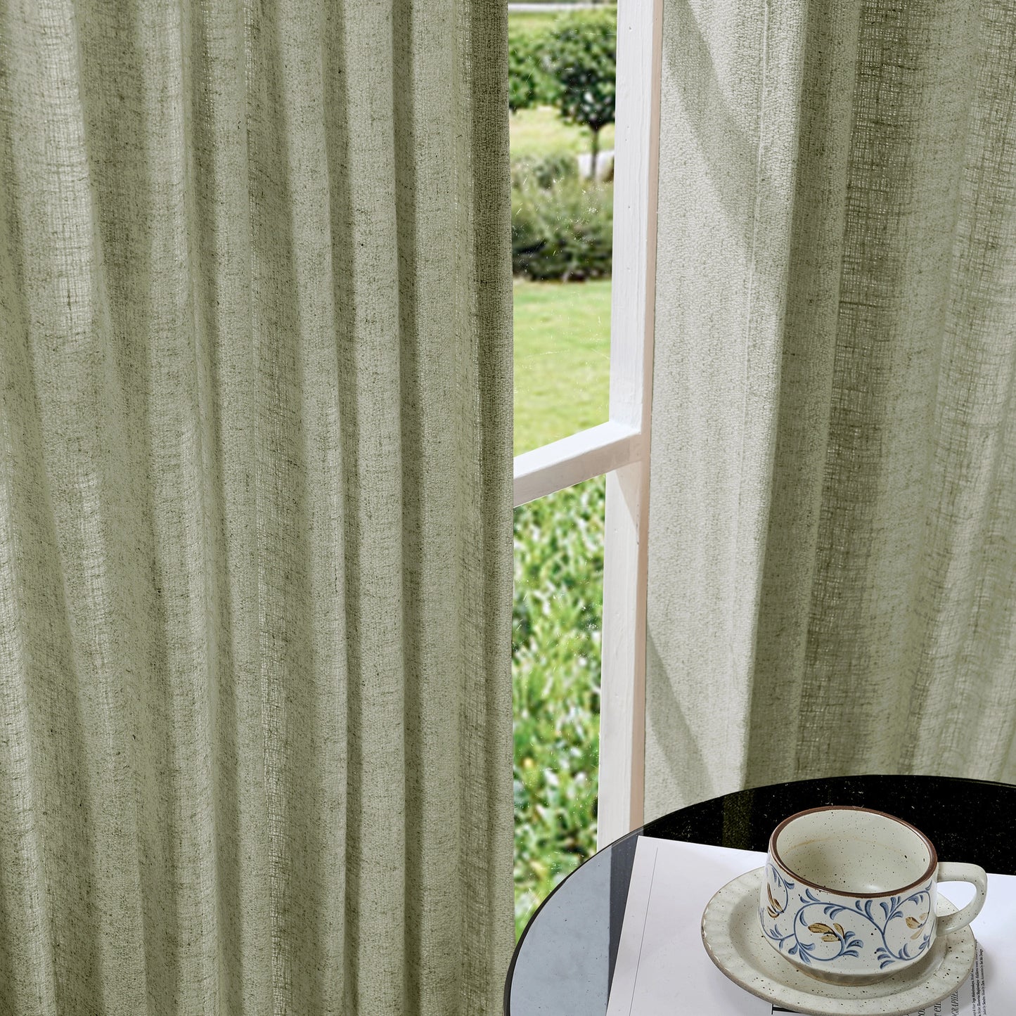 Soft graphite gray curtains made of viscose, polyester, and linen, with a cup and saucer on a table in the foreground.