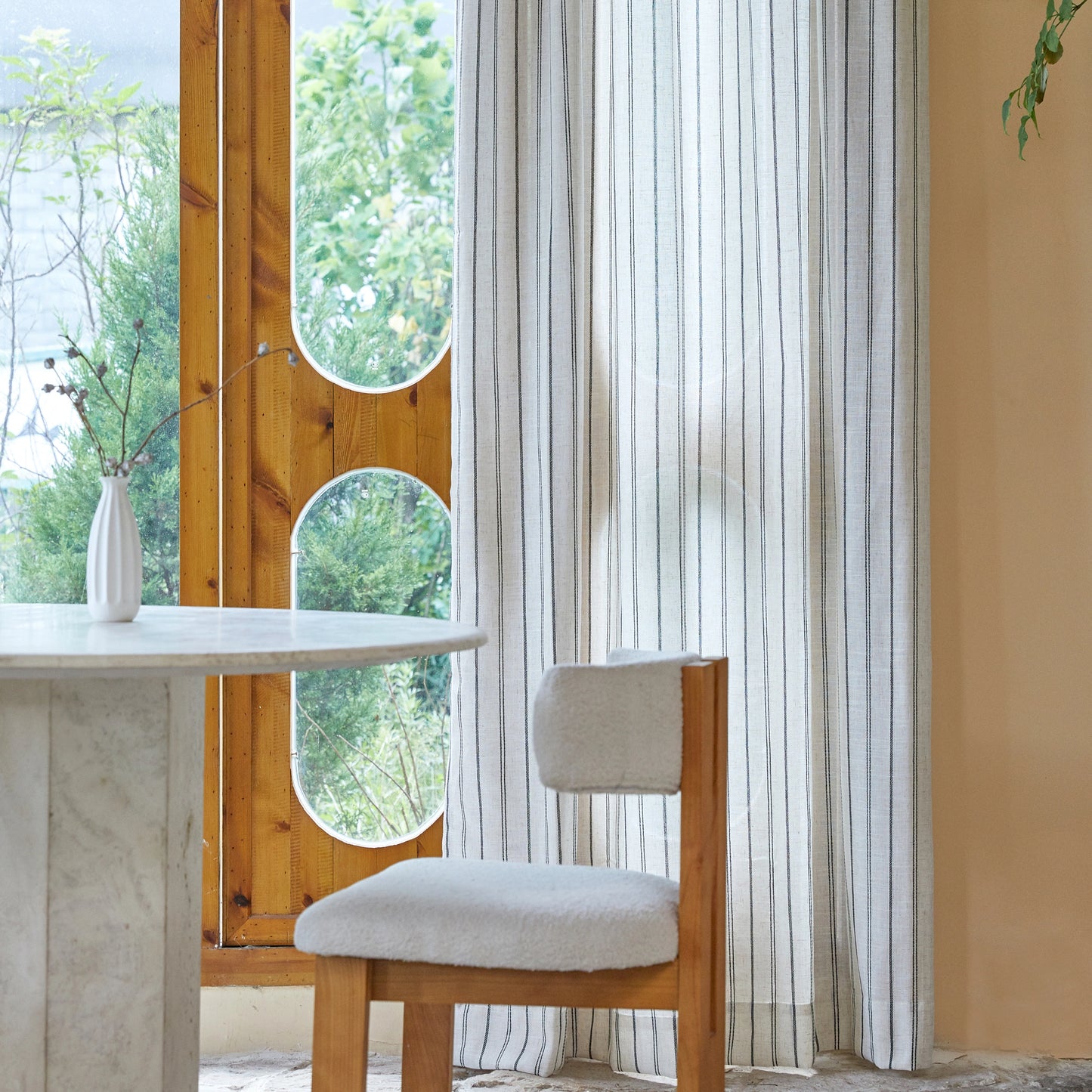 Modern interior with a table, chair, and farmhouse curtain featuring an uneven linear pattern.