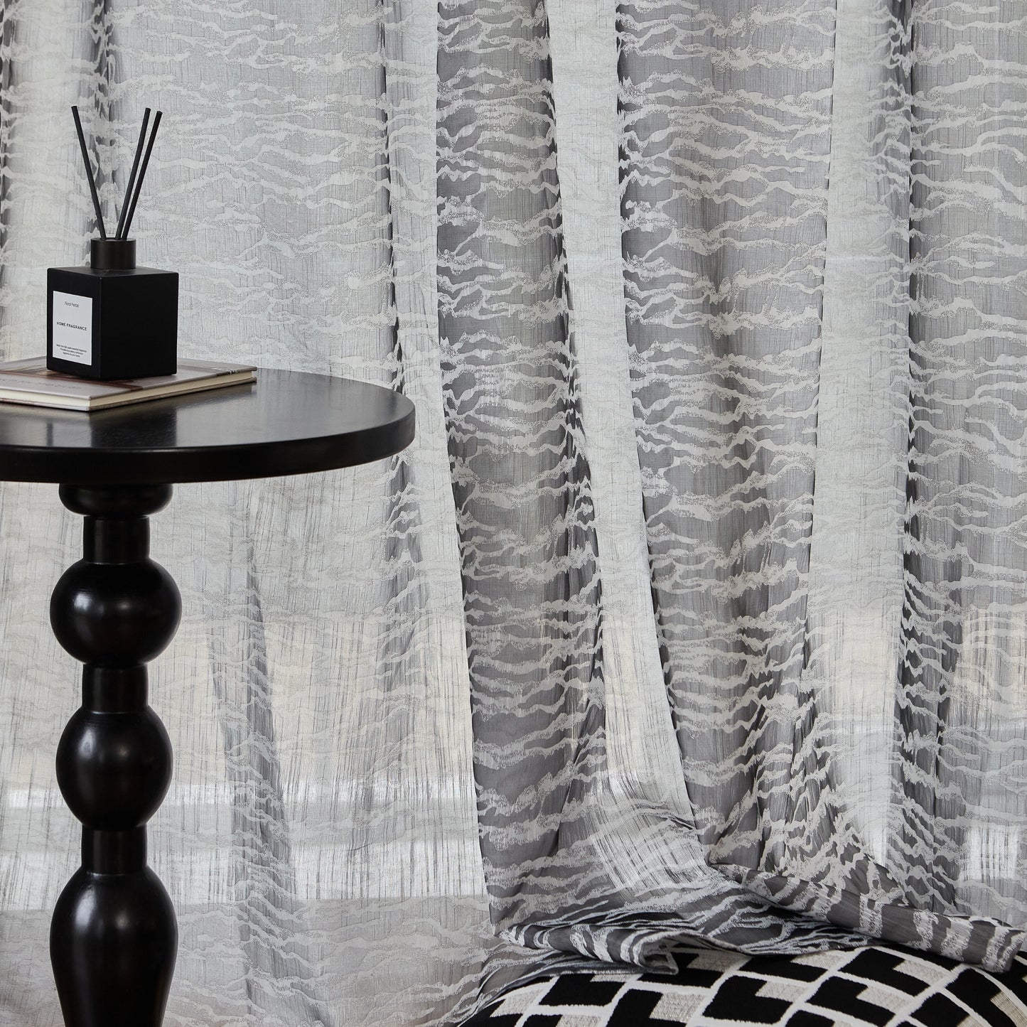 Graphite-gray textured curtains , paired with a black side table and monochrome cushion for a modern look.
