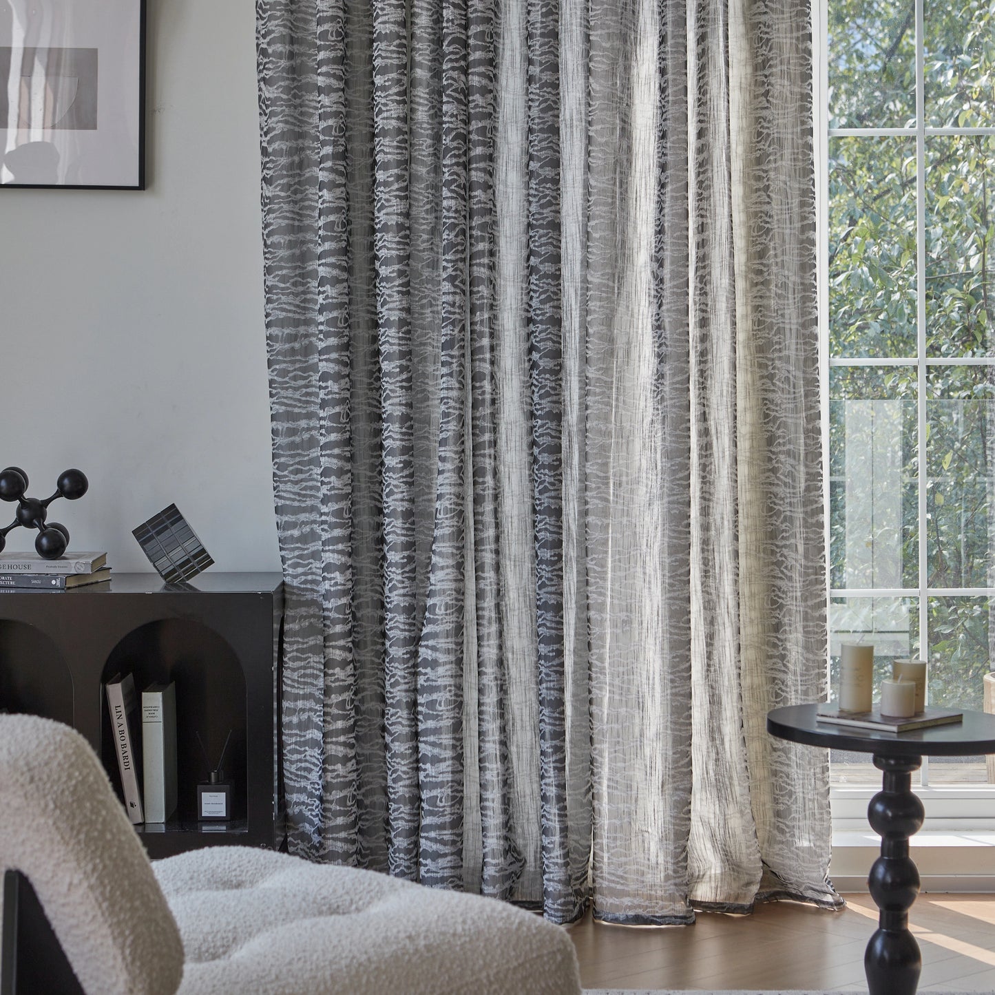 A living room featuring large windows dressed with graphite-gray curtains, complemented by a sofa and a table.