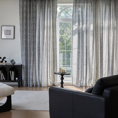 Living room styled with slate-gray contemporary drapery, with a sofa, rug, and table in the space.