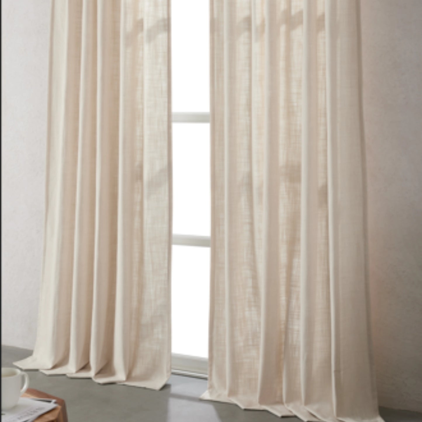 Ivory linen-polyester blend curtains hanging in front of a window with a neutral background.
