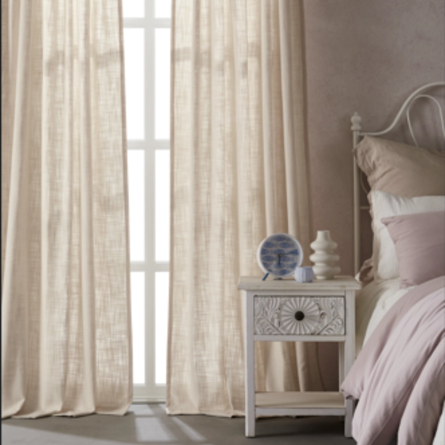 Bedroom with pale ivory polyester-linen combination drapery panels, a nightstand, and a bed with pink bedding.