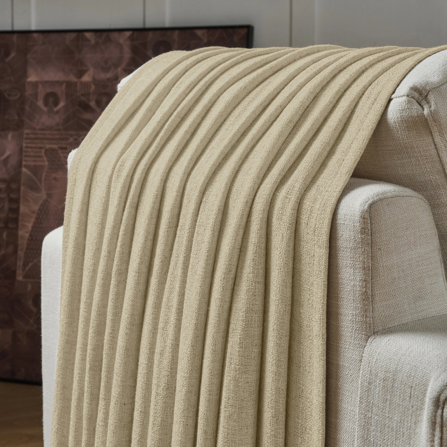 Khaki textured curtain draped over a sofa, with a decorative wall in the background.