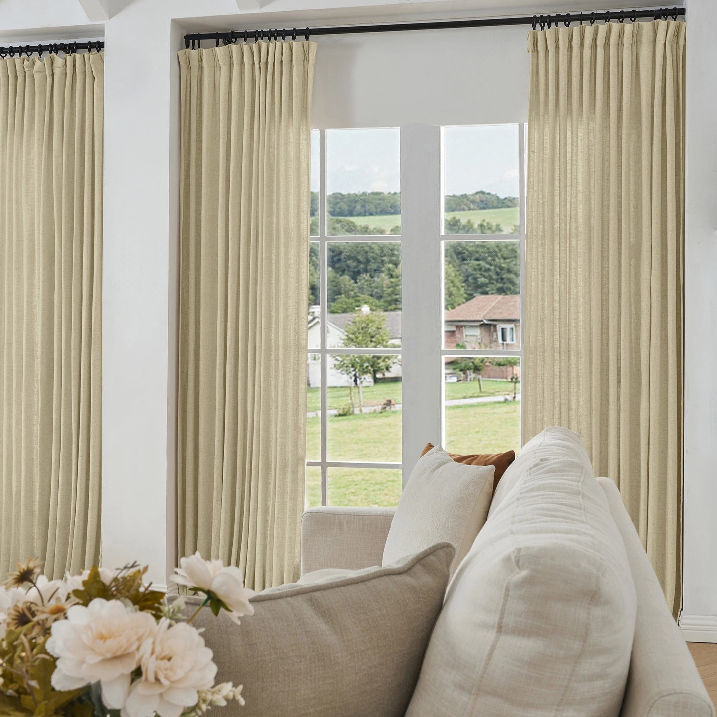 Living room with beige khaki curtains made of viscose, polyester, and linen, a sofa, and a view of greenery outside.