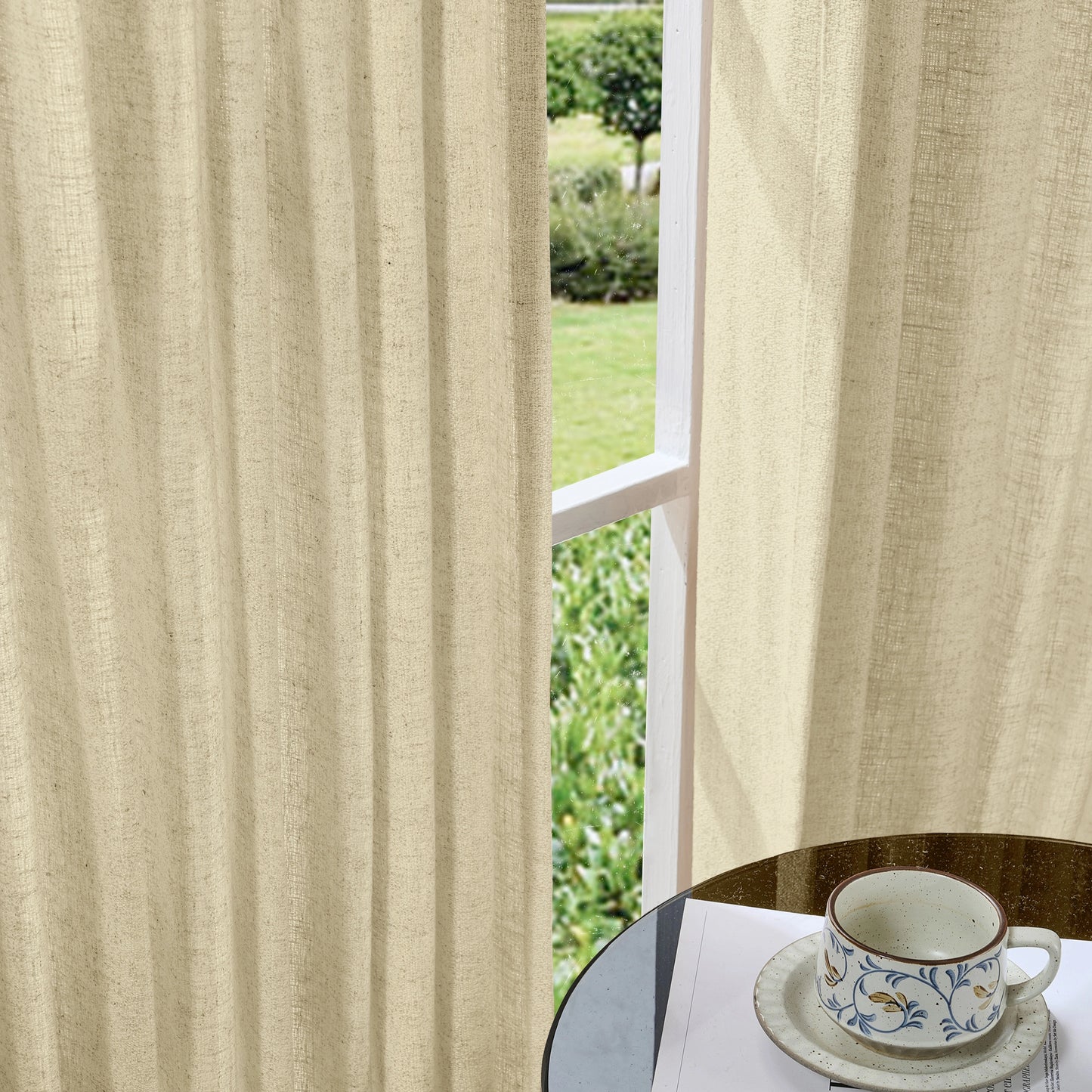 Soft khaki curtains made of viscose, polyester, and linen, with a cup and saucer on a table in the foreground.