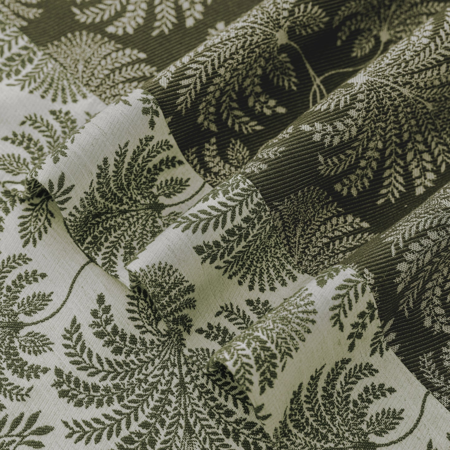 Folded curtain fabric highlighting layered leaf patterns and a woven texture