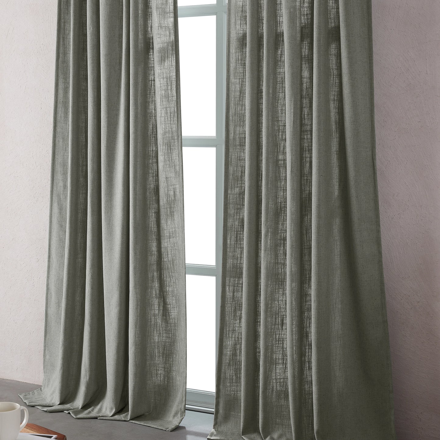 Light gray linen-polyester blend curtains hanging in front of a window with a neutral background.