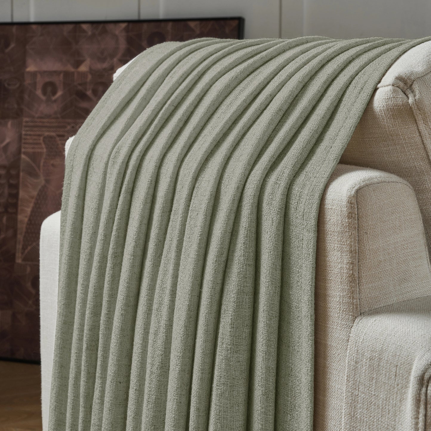 Light gray textured curtain draped over a sofa, with a decorative wall in the background.