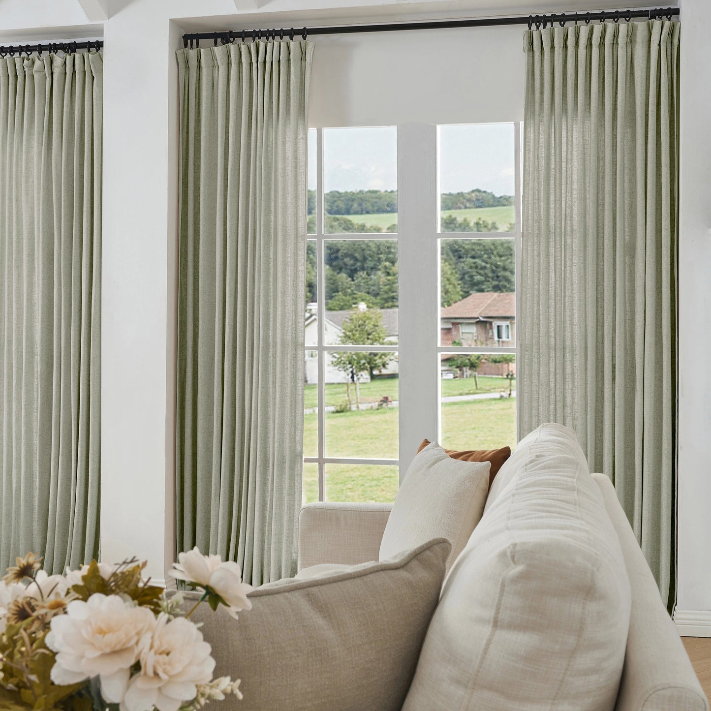 Living room with pale gray curtains made of viscose, polyester, and linen, a sofa, and a view of greenery outside.