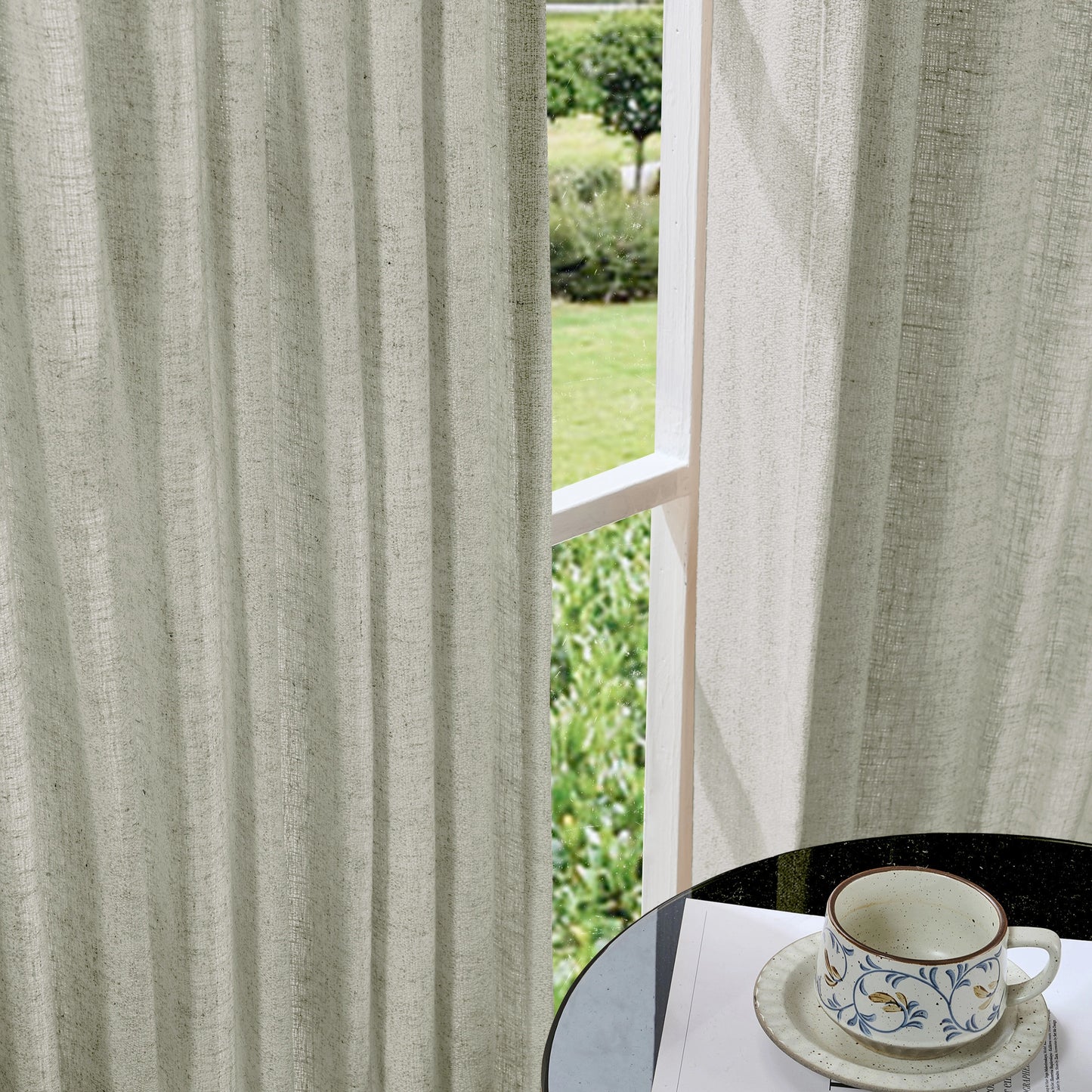 Soft dove gray curtains made of viscose, polyester, and linen, with a cup and saucer on a table in the foreground.