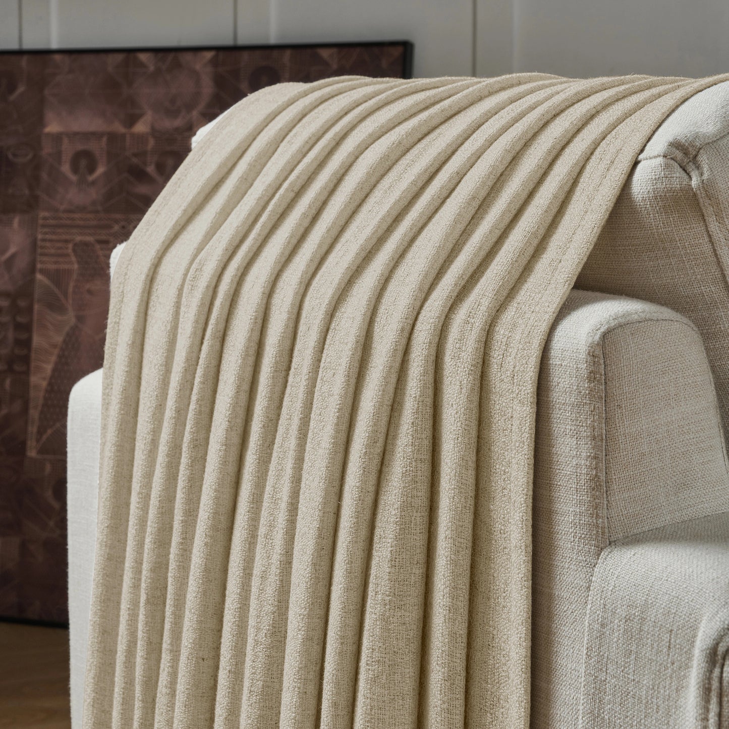 Light ivory textured curtain draped over a sofa, with a decorative wall in the background.