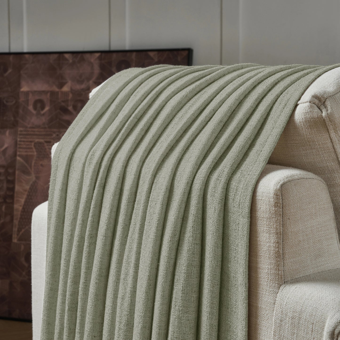 Medium gray textured curtain draped over a sofa, with a decorative wall in the background.