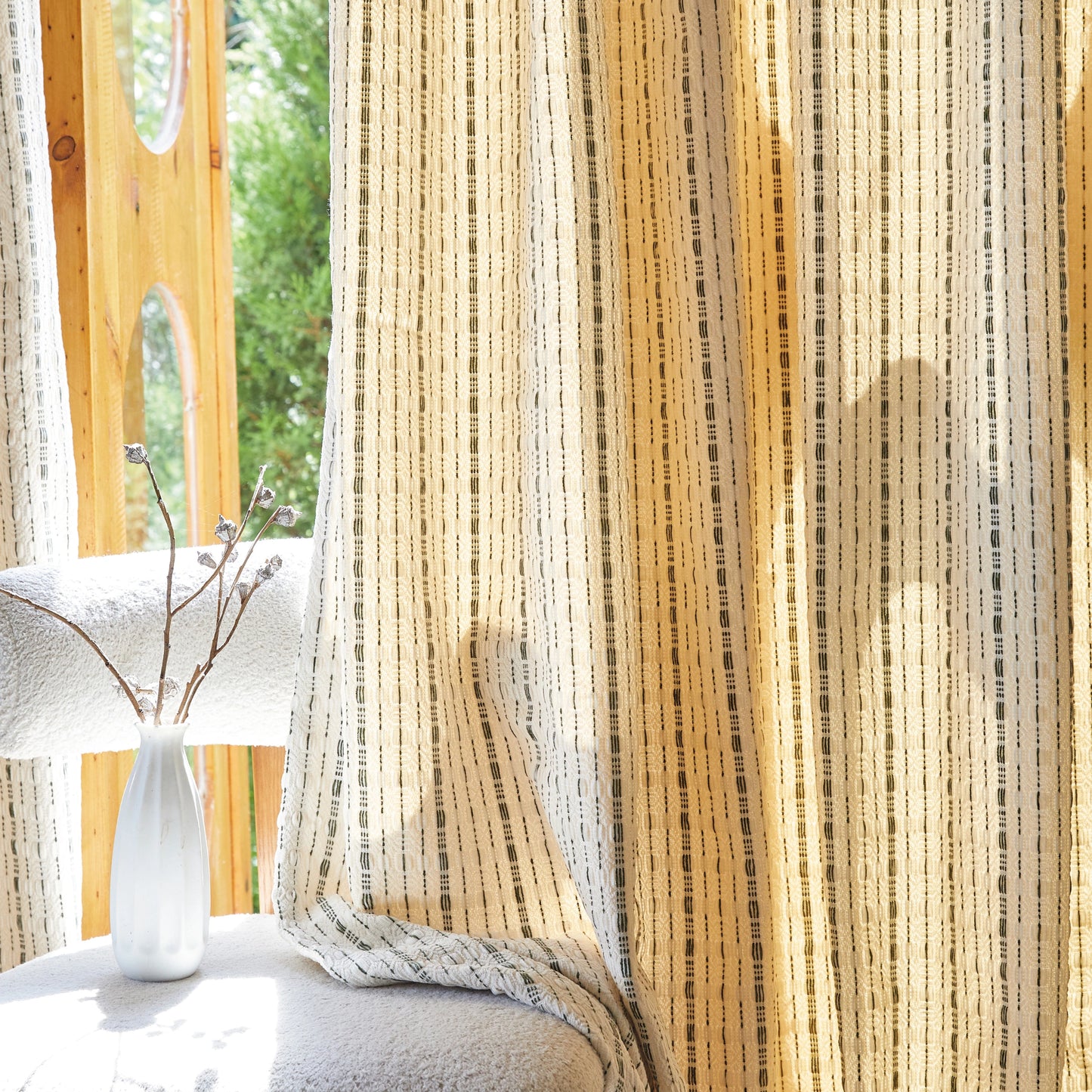 Oatmeal polyester modern curtain with subtle raised black lines draped over a chair, vase placed on the chair.
