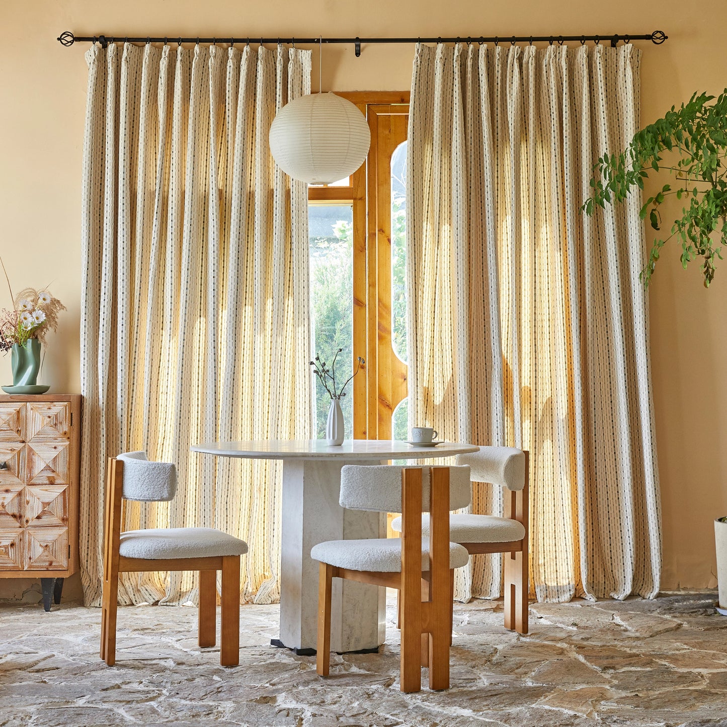 Dining table and chairs in front of tan polyester modern curtains with raised black linear pattern.
