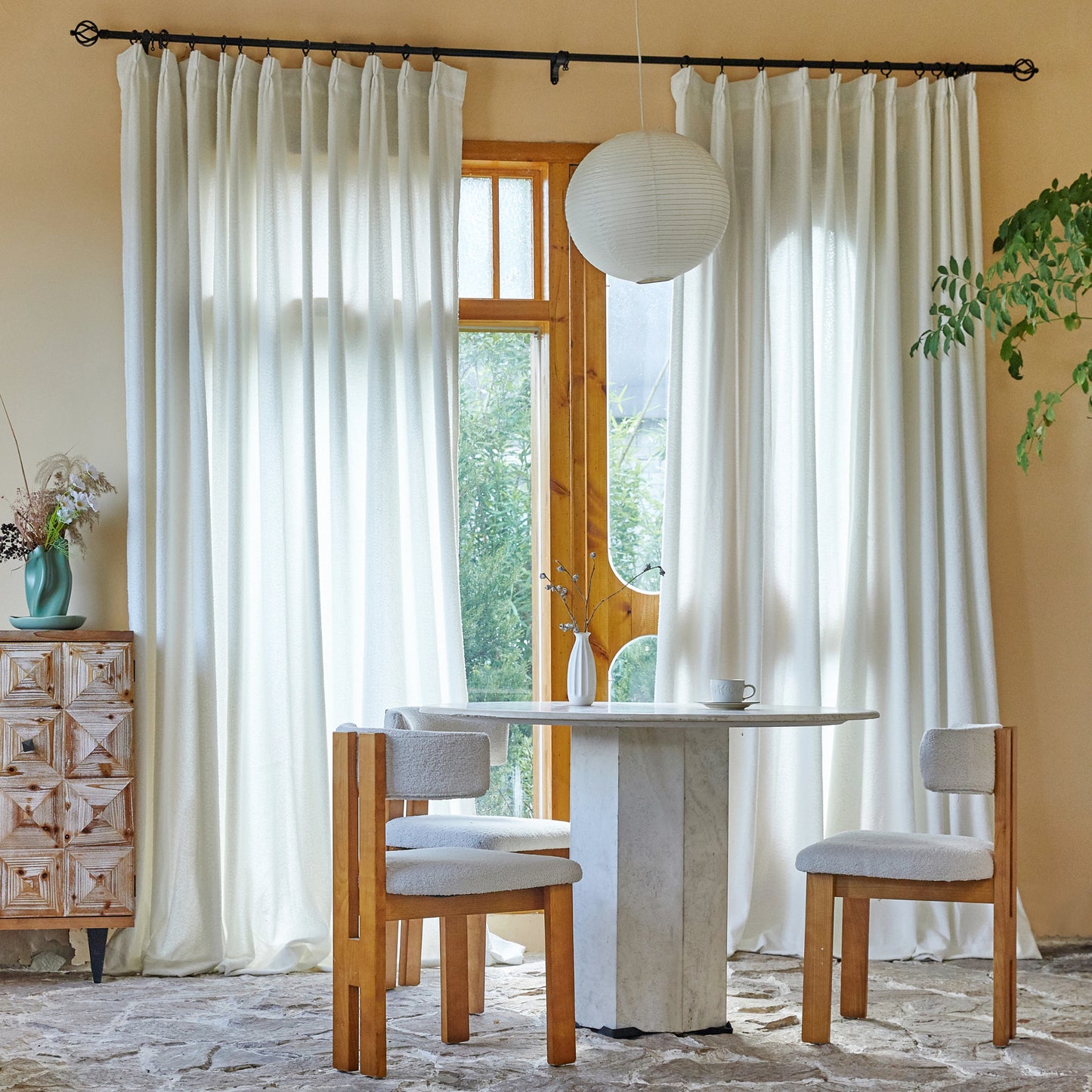 Dining room featuring soft alabaster terry gauze yarn curtains, marble table, and wooden chairs.