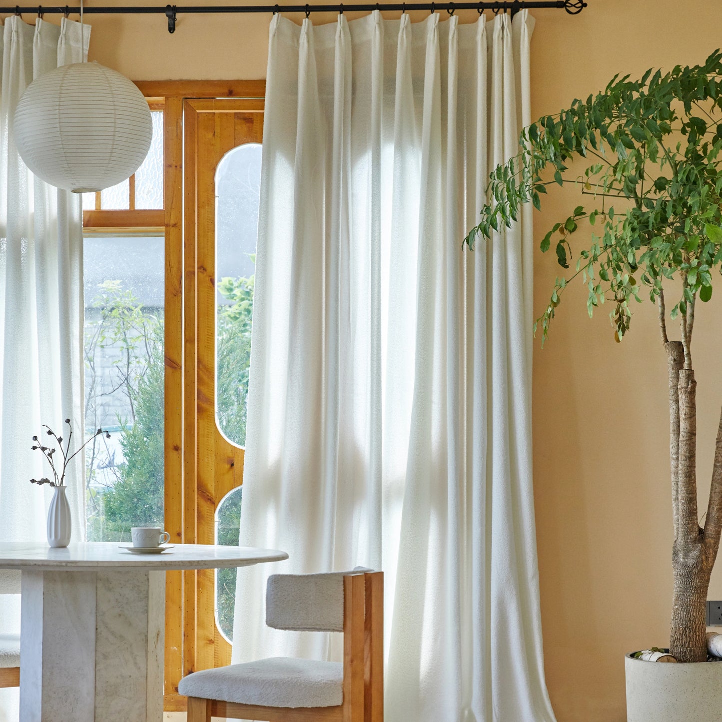 Dining room with lightweight off-white terry yarn curtain panels, table, chair, and potted plant.