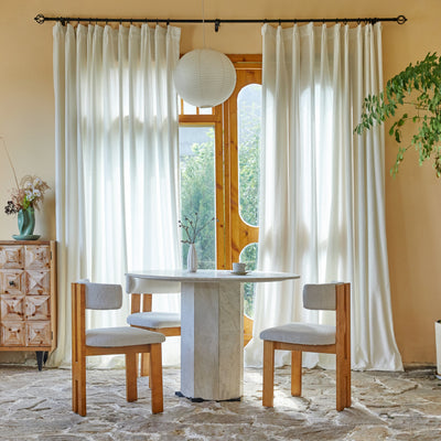 Dining room with marble table and wooden chairs, large windows with contemporary snow terry yarn drapery panels.