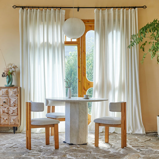 Dining room with marble table and wooden chairs, large windows with contemporary snow terry yarn drapery panels.