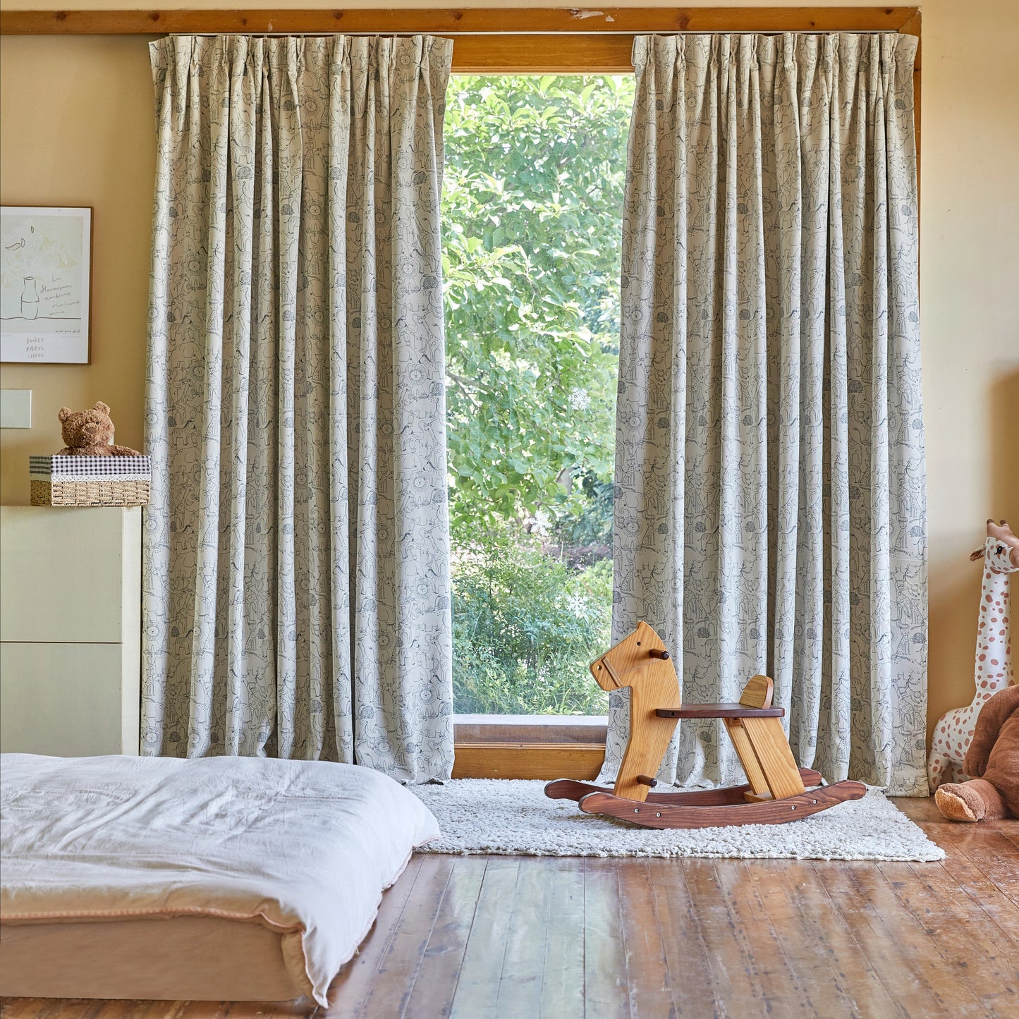Children's room with patterned curtains, rocking horse, and stuffed giraffe.