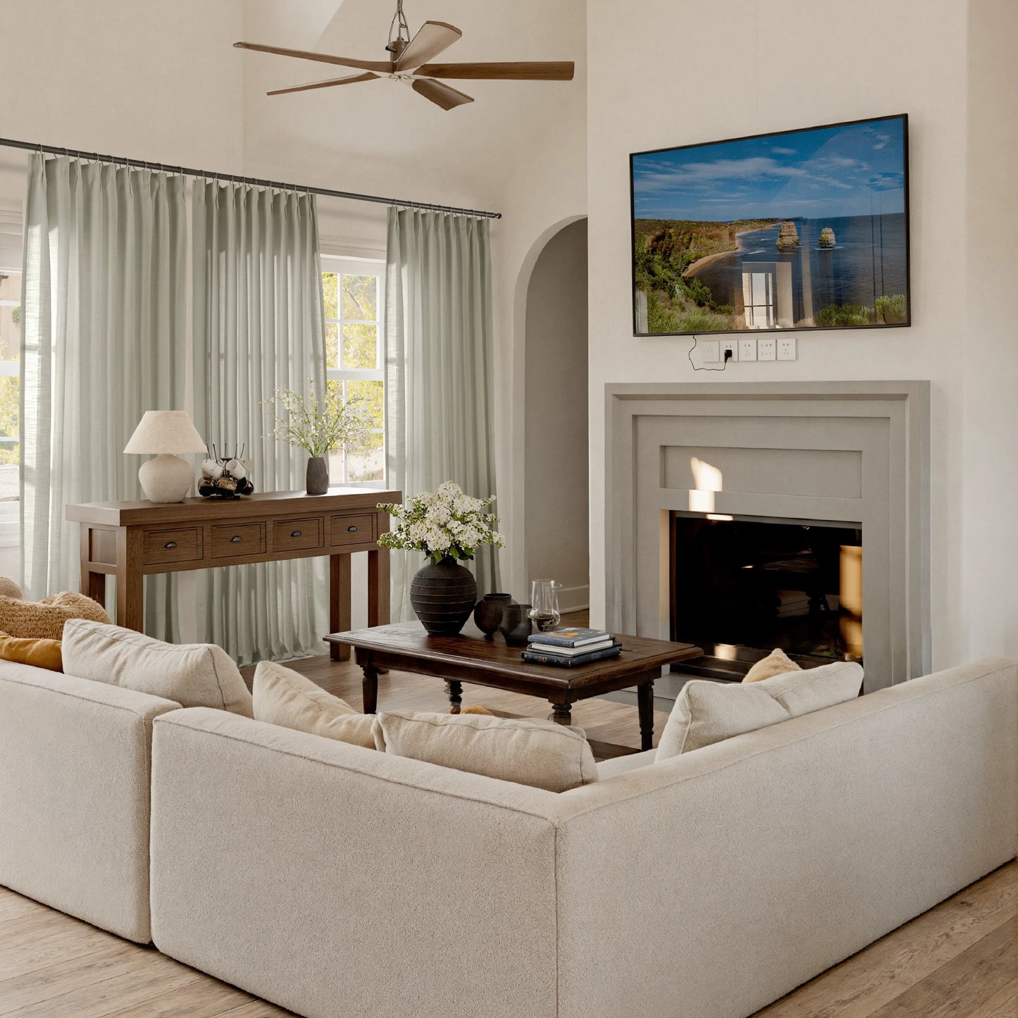 Living room with pebble curtains, beige sofa, coffee table, and TV mounted on the wall.