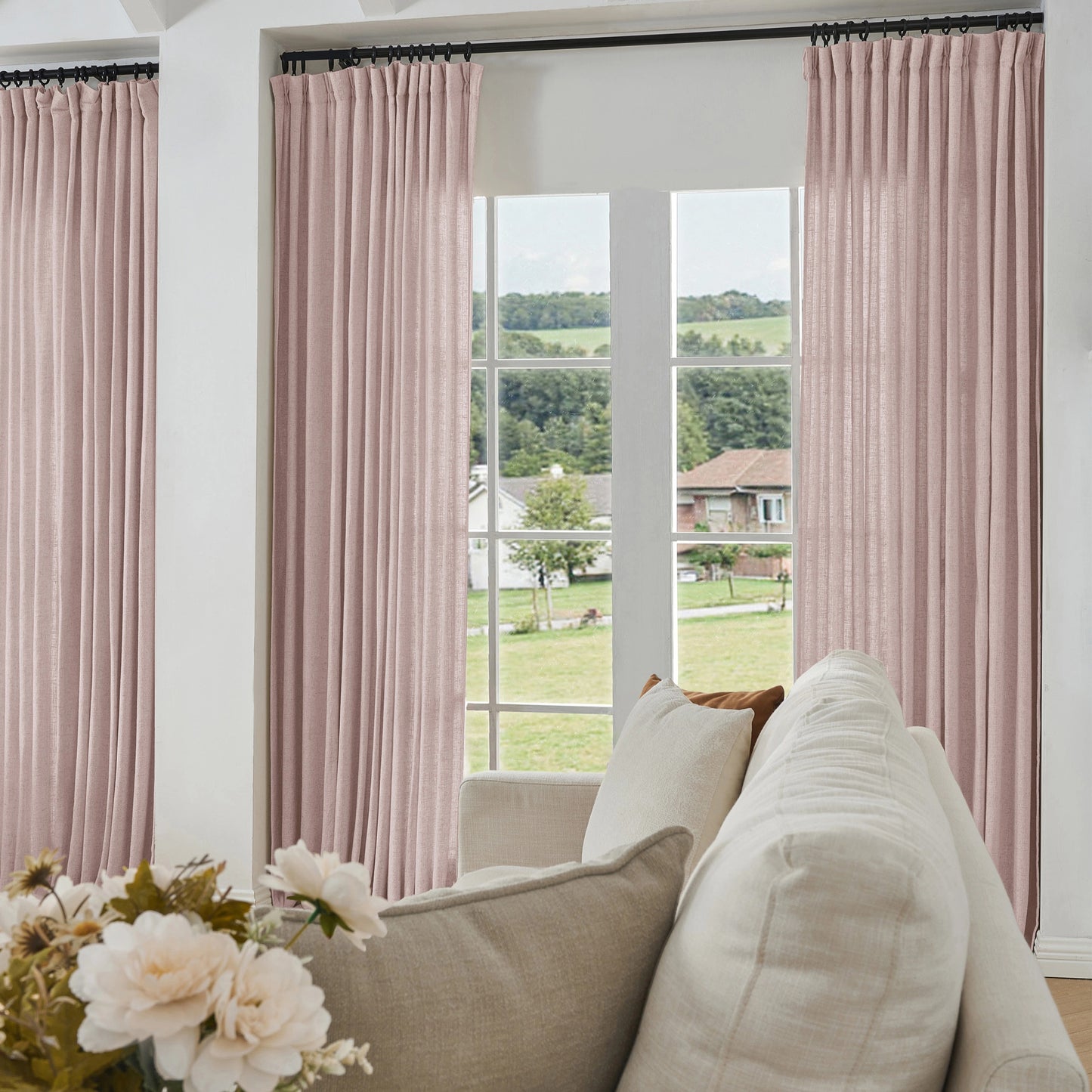 Living room with dusty pink curtains made of viscose, polyester, and linen, a sofa, and a view of greenery outside.