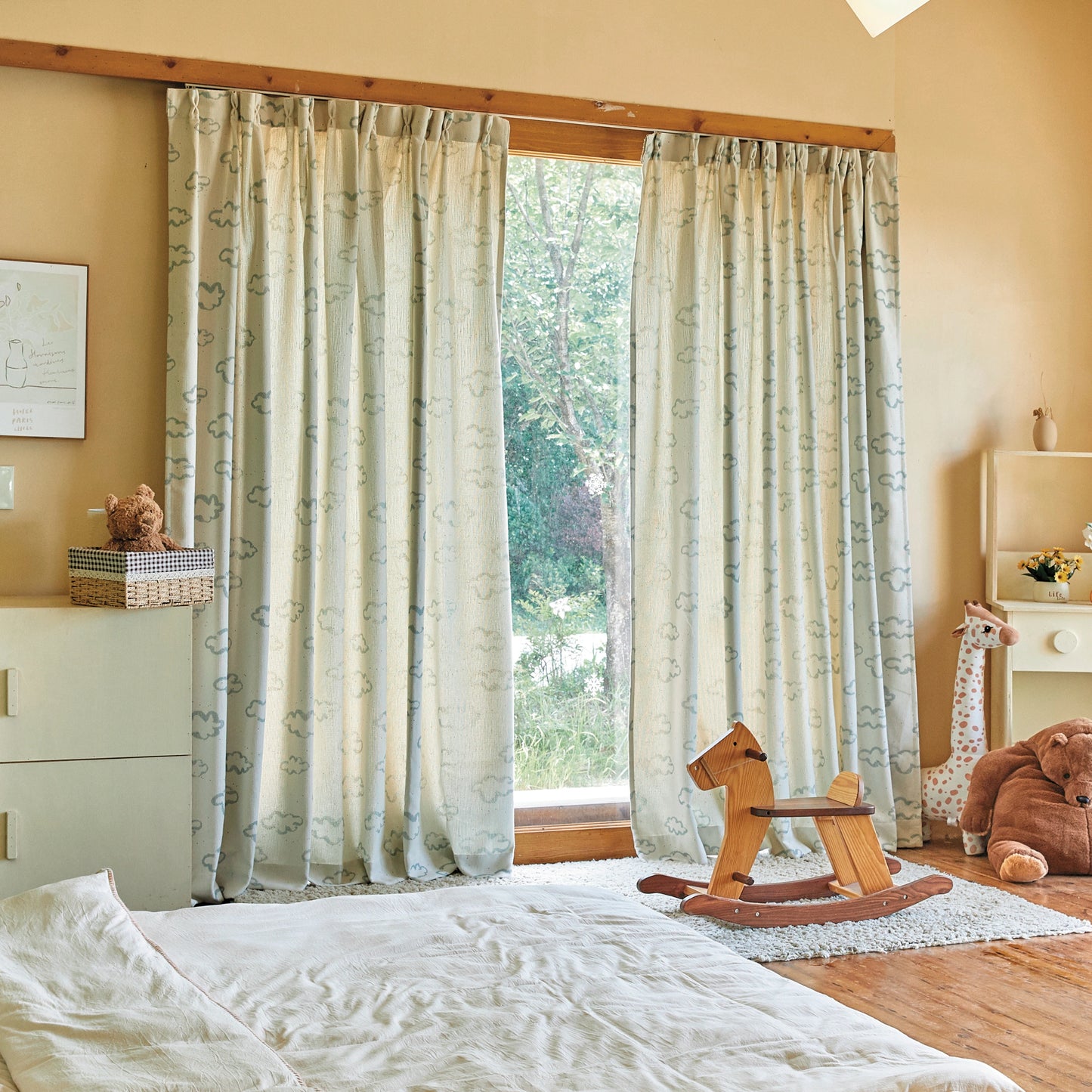 Blue line white cloud curtain panels in a bedroom with a white-sheeted bed and toys placed around the room.