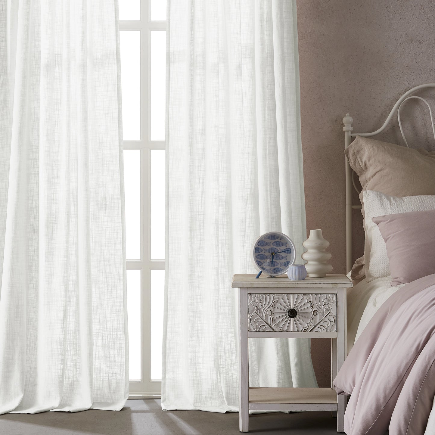 Bedroom with light snow-white polyester-linen combination drapery panels, a nightstand, and a bed with pink bedding.