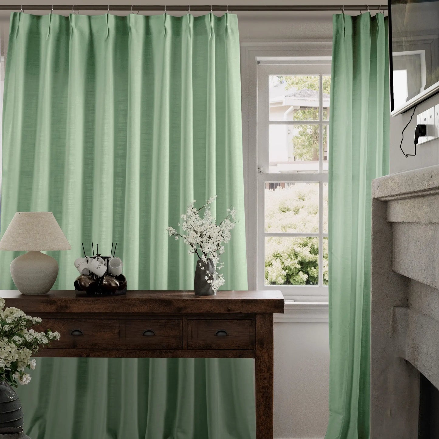 Celadon curtains hanging in a room with a wooden table and lamp.