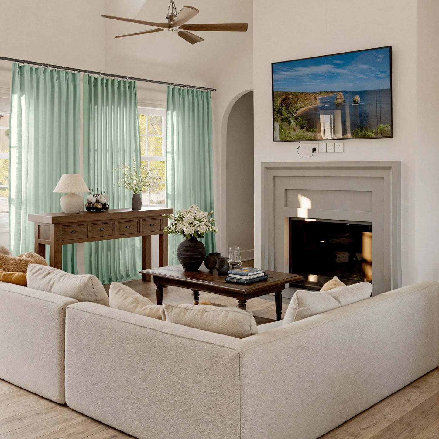 Living room with pistachio curtains, beige sofa, coffee table, and TV mounted on the wall.