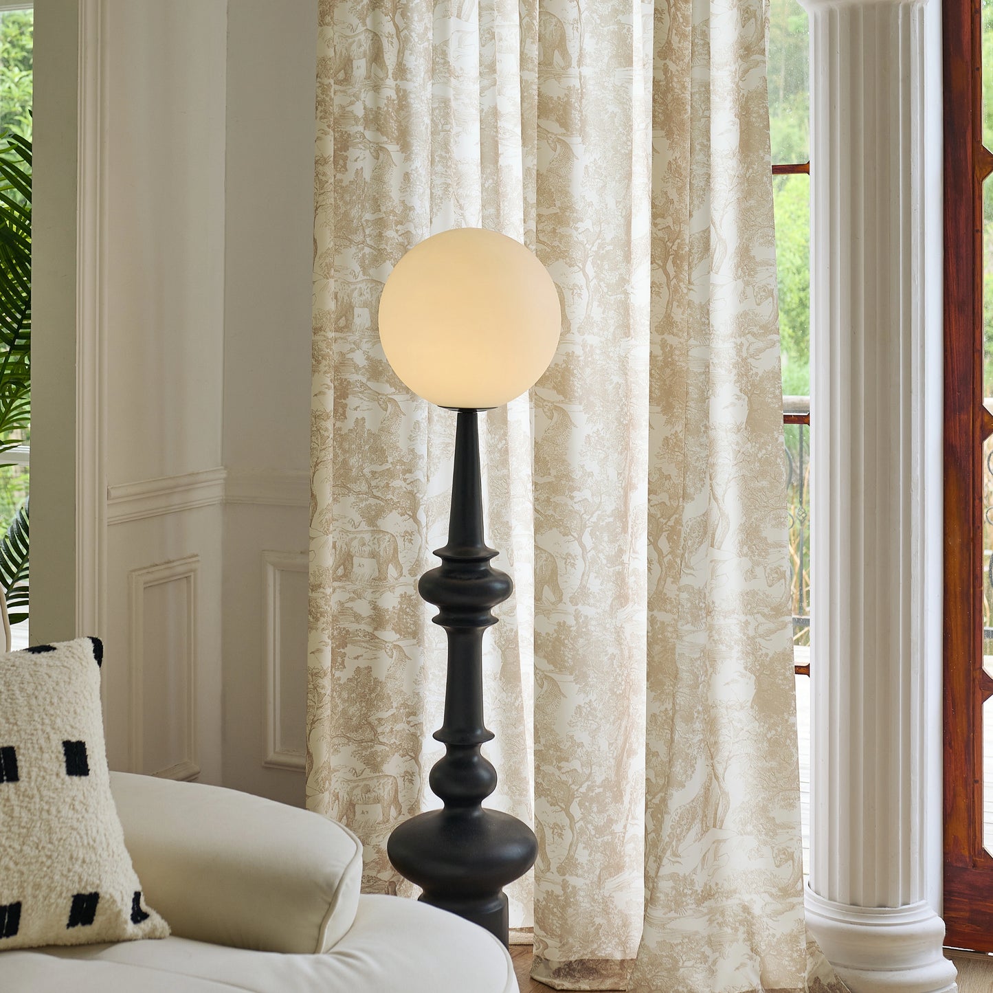 Living room interior with a white sofa, decorative pillow, floor lamp, and hazel toile gauzy curtains.