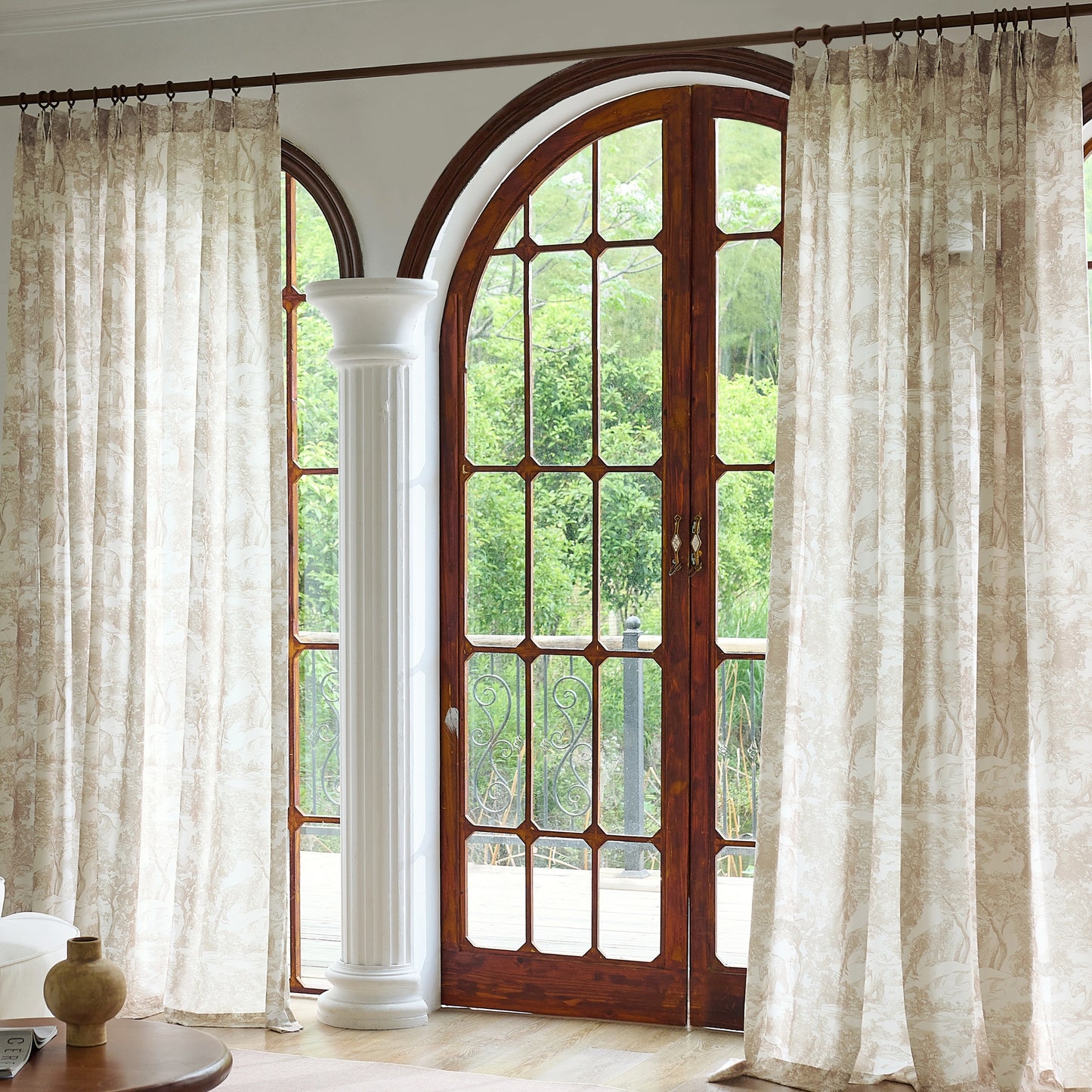 Pinch pleat cocoa toile gauzy curtains with a wooden door and white columns in the background.