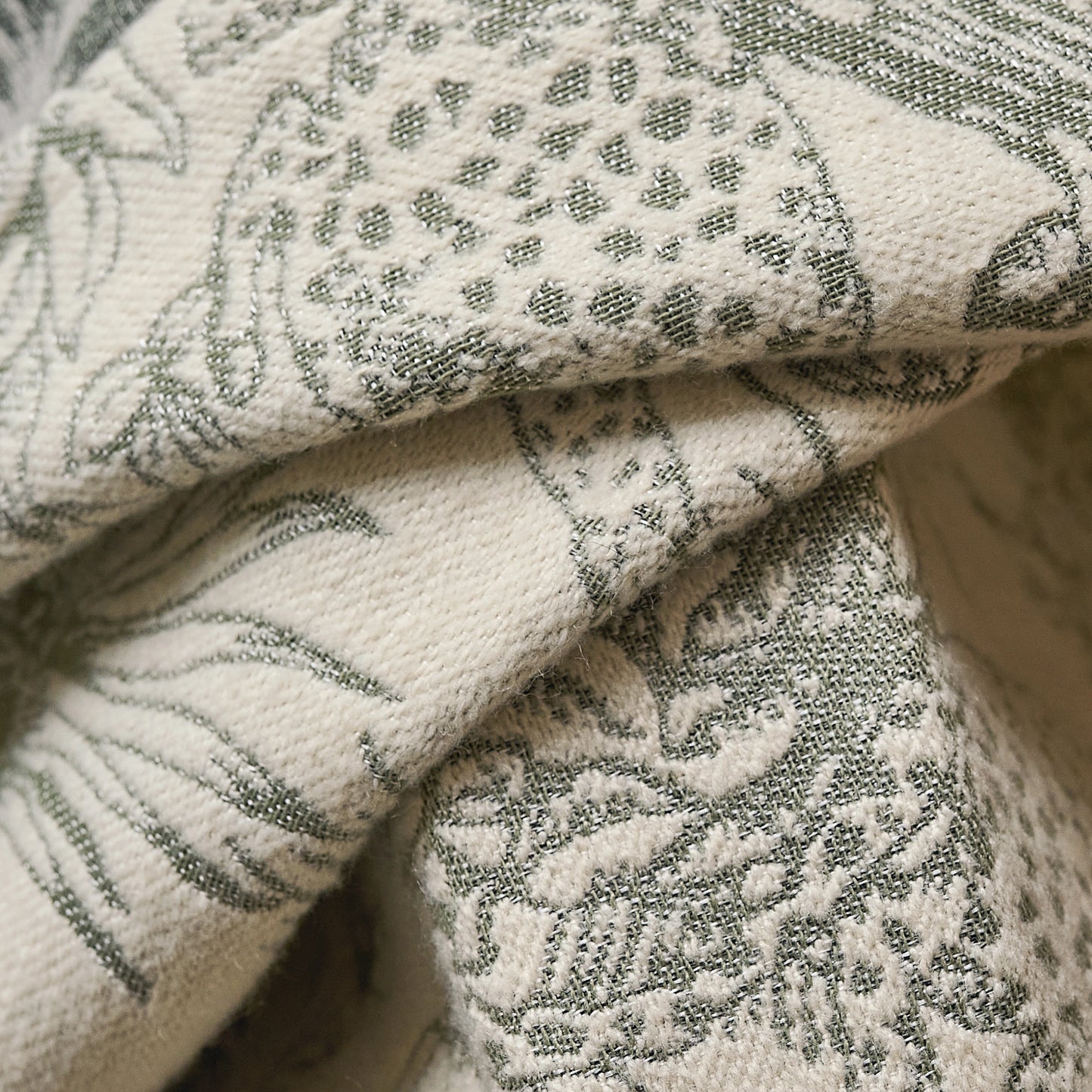 Textured fabric detail of moss toile curtains, showing intricate leafy patterns on soft cashmere-inspired textile.