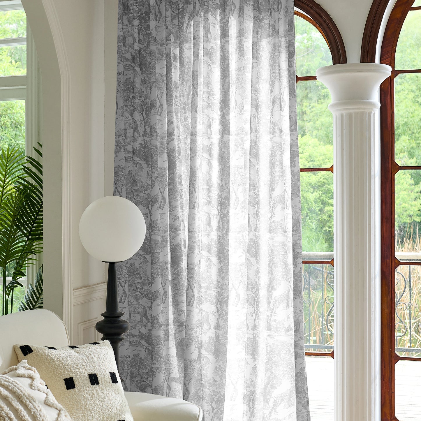 Living room with white armchair, decorative pillow, and patterned gray curtain.