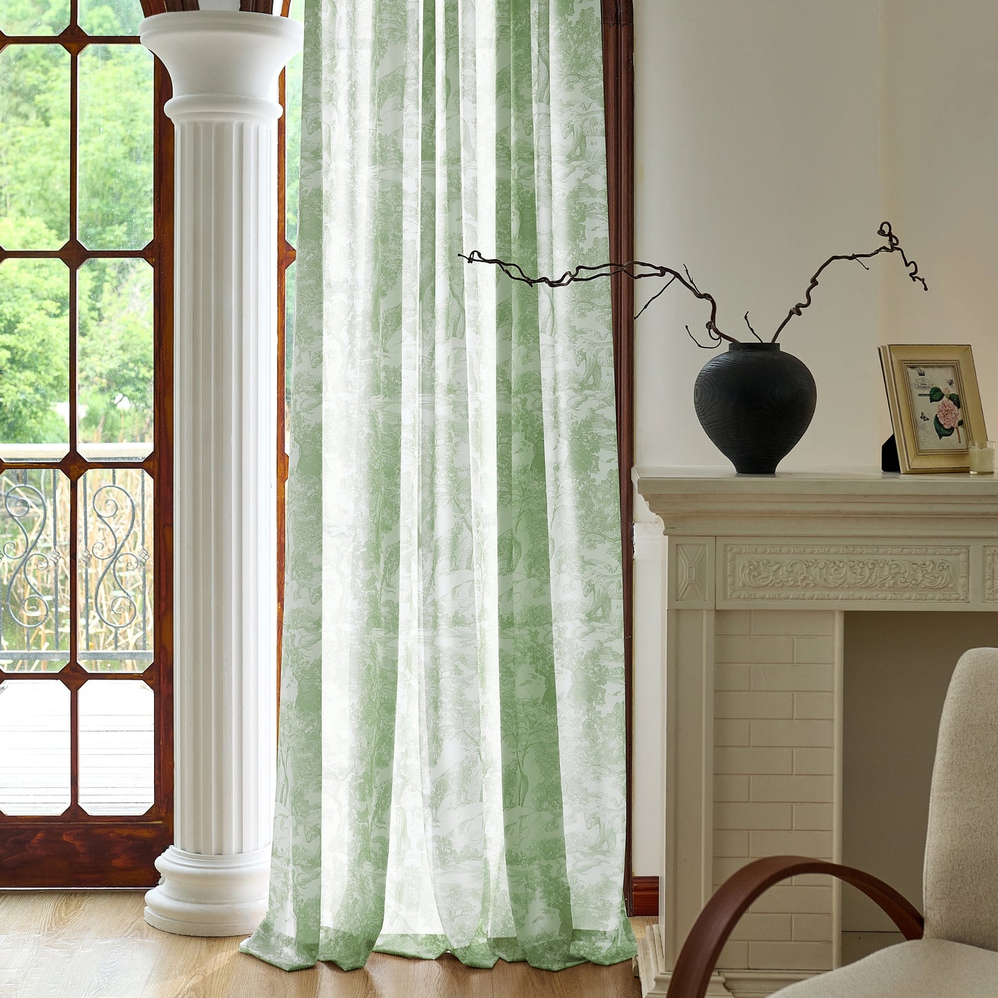 Green sheer with toile pattern in a room with a fireplace and decorative items.