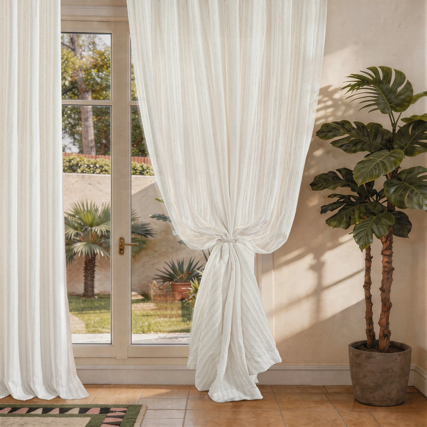 White curtains hanging in front of a glass door with a potted plant nearby.